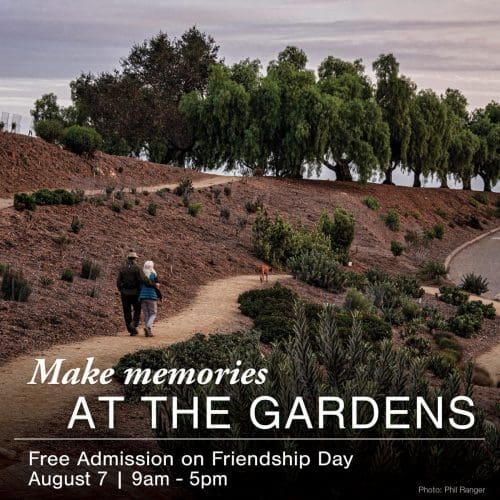 Text: 'Make memories at the gardens', Background: A couple walks the trails at VBG with their dog (Photo: Phil Ranger)