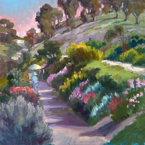 A winding pathway lined with colorful flowers and bushes, meticulously designed by Anette Power, extends through a hilly landscape under a partly cloudy sky.