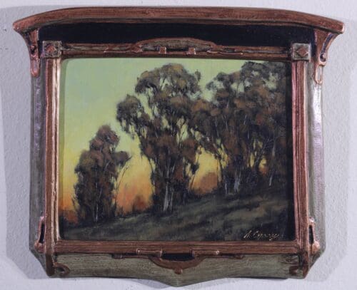 A framed painting depicts a group of trees on a hillside at sunset. The frame has distinctive, ornate details.