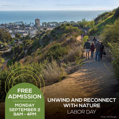 A group of people walking on a hillside trail overlooking an ocean and town. The image text reads, "Free Admission, Monday September 2, 9AM - 4PM. Unwind and reconnect with nature this Labor Day.